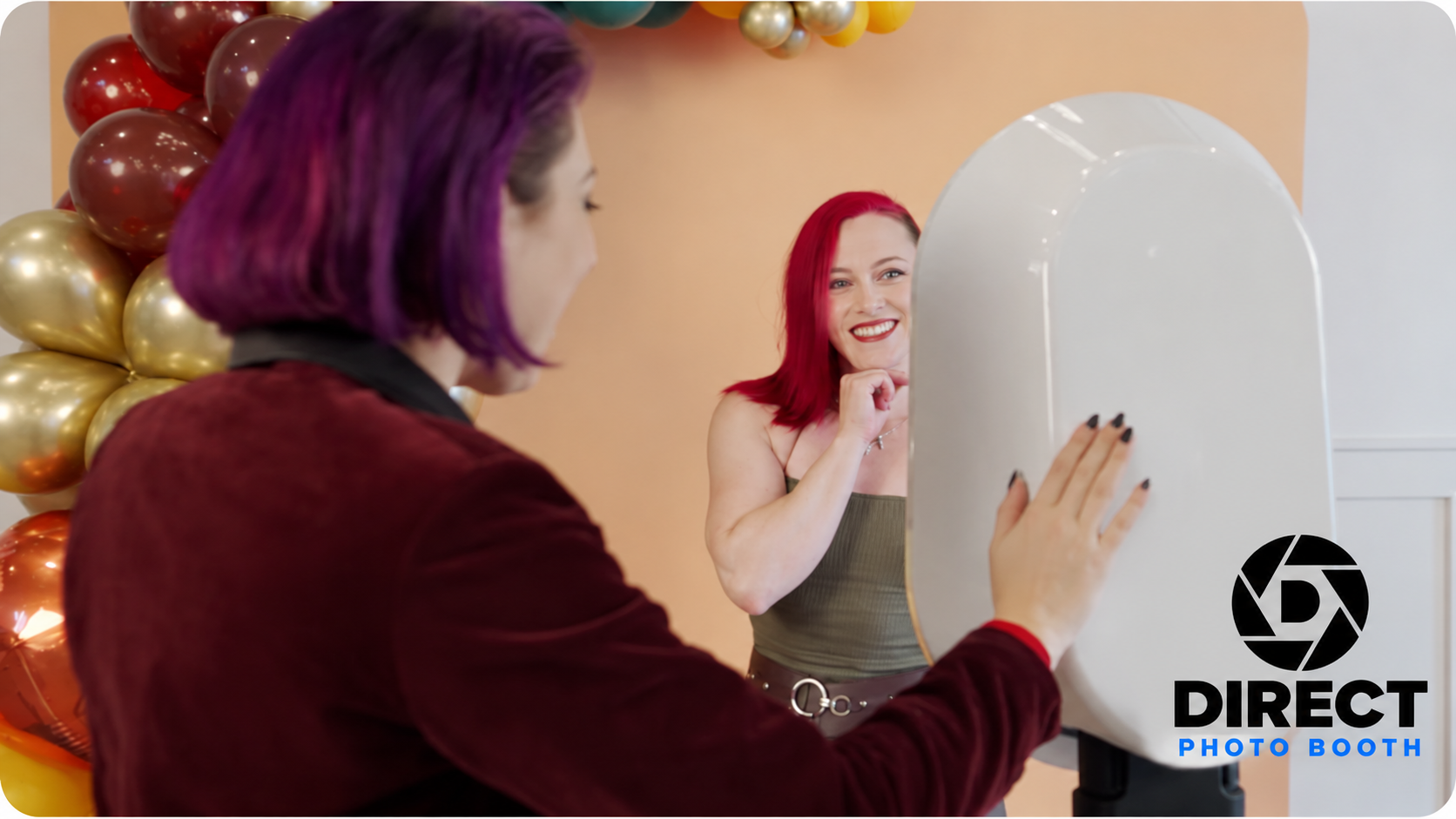 Guests enjoying a white photo booth beside a colourful balloon display